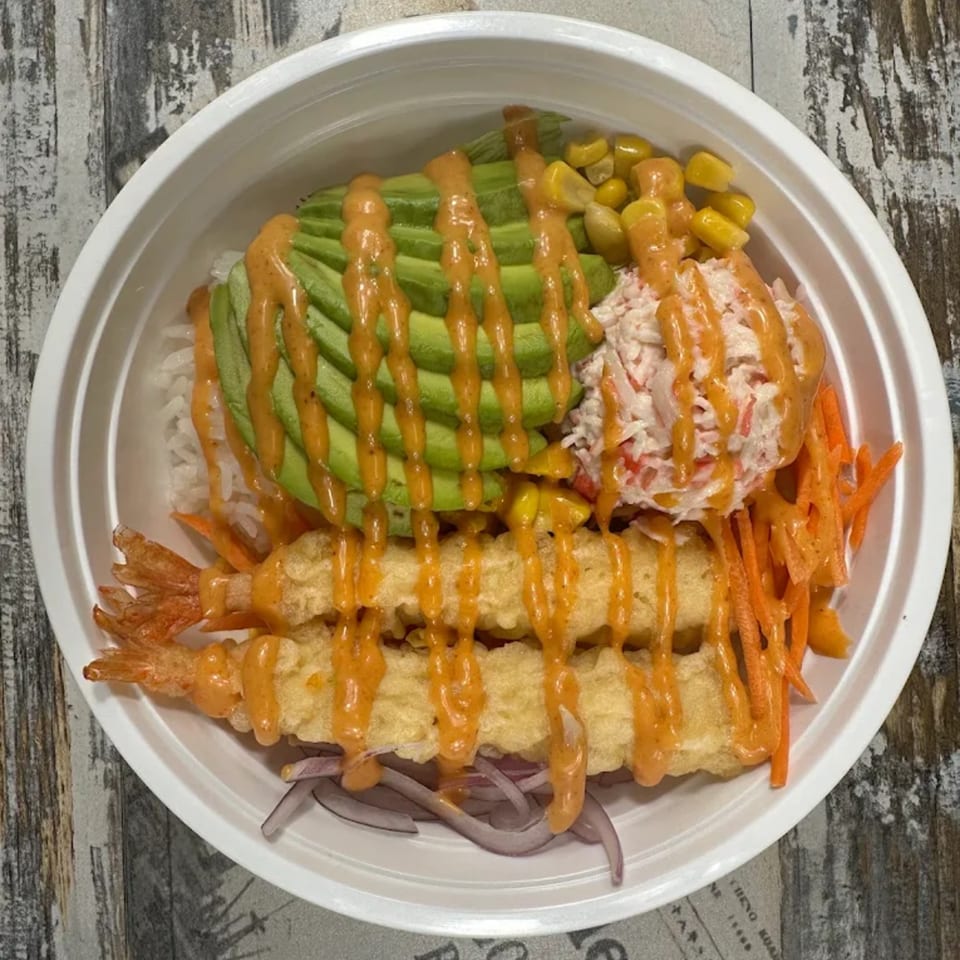 A poke bowl with tempura shrimp, avocado, corn, crab salad, carrots, and red onions.