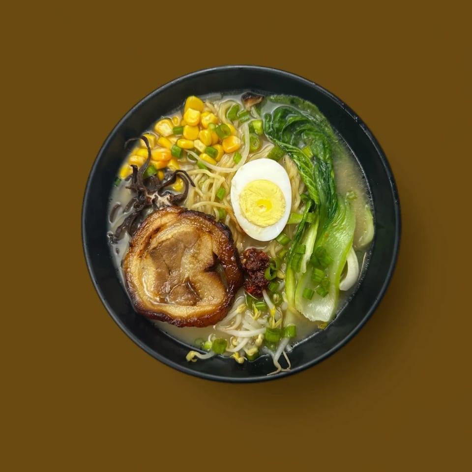 A bowl of ramen with pork, corn, bok choy, egg, bean sprouts, and scallions.